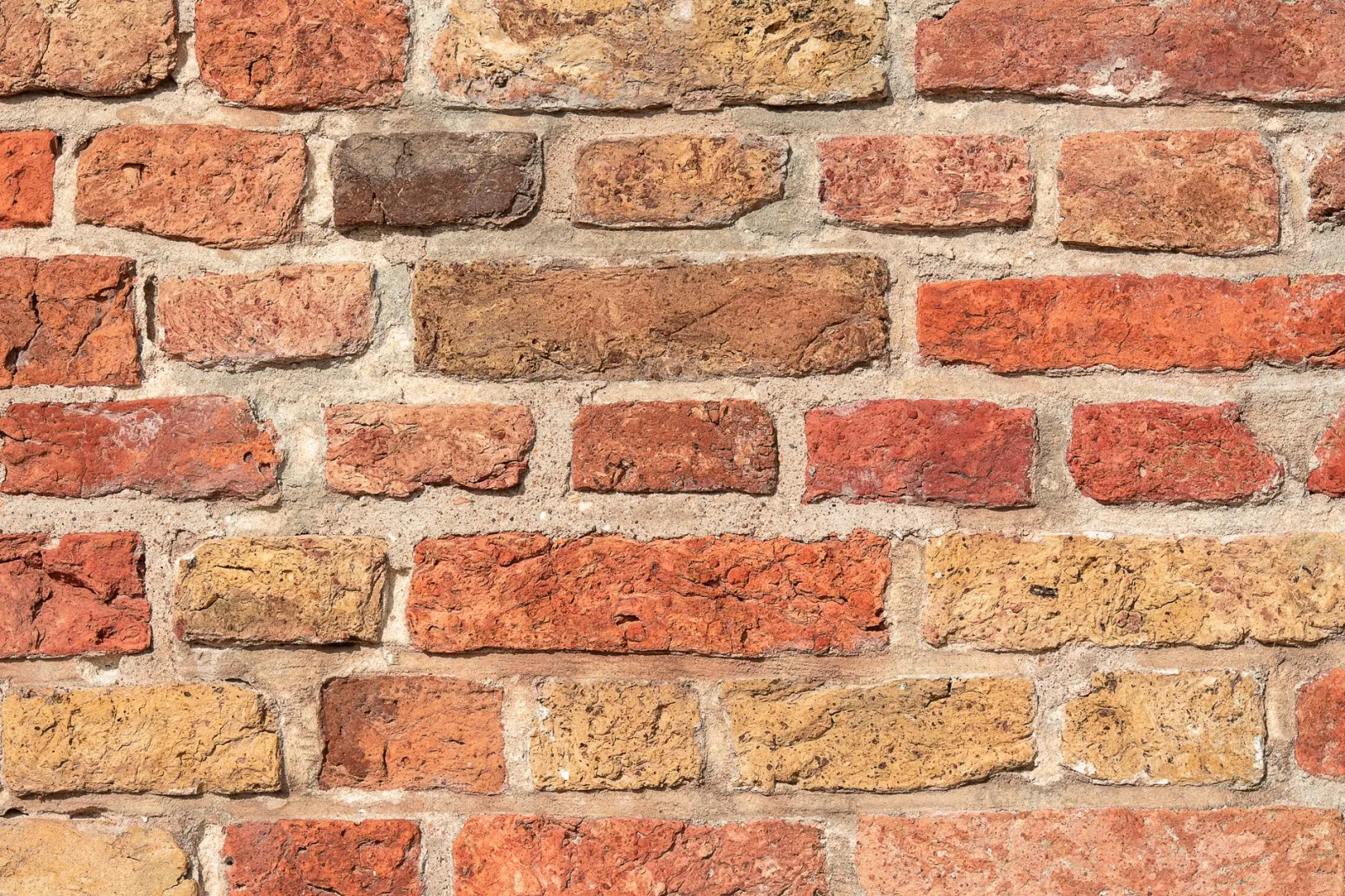 Detailed image of a rough, multicolored brick wall texture for backgrounds or design.